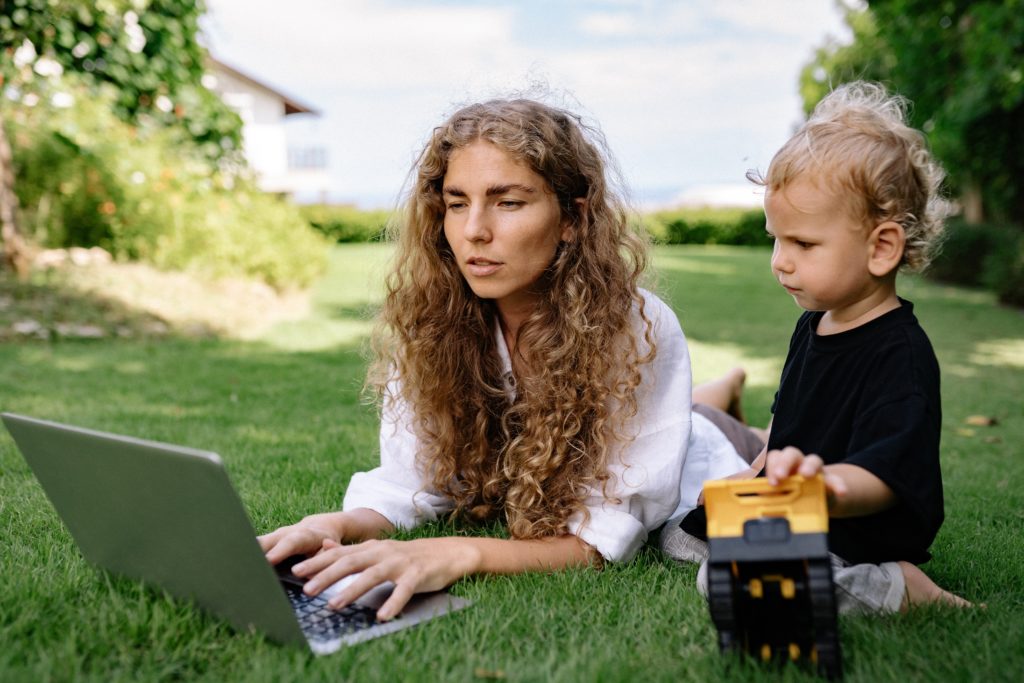 Woman laying on grass working on laptop