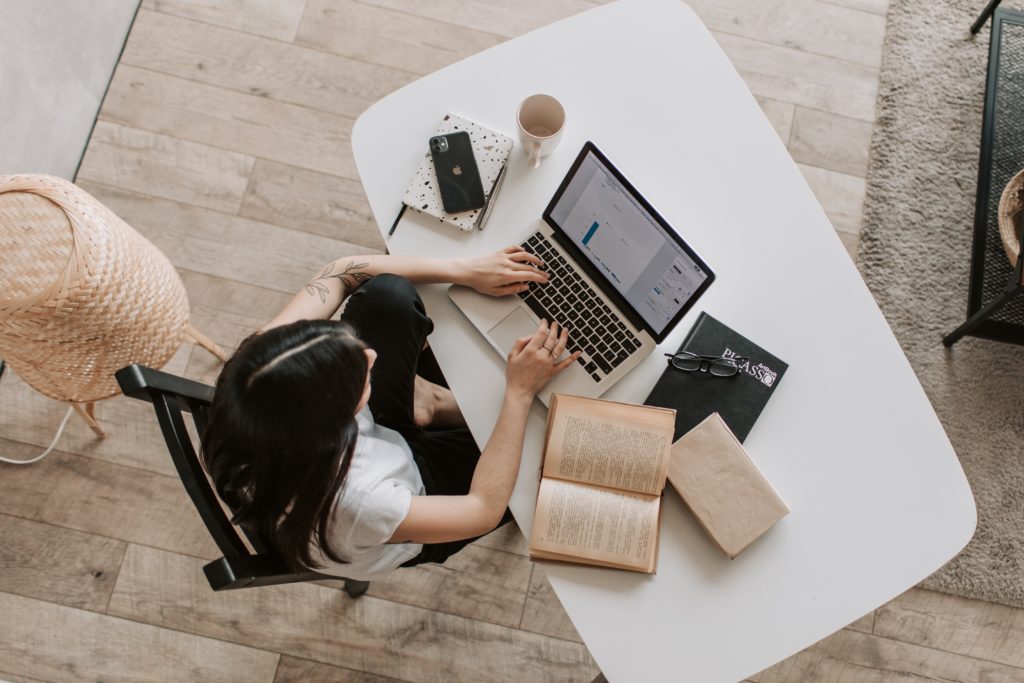 Woman learning at desk with book and laptop