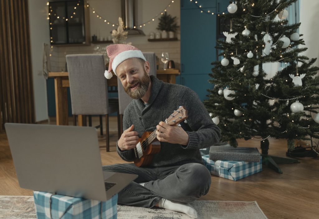Man in Santa hat playing guitar in front of laptop